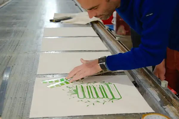 Contrôle de la teinte au nuancier Pantone sur la table de sérigraphie Contrôle de la teinte au nuancier Pantone sur des toiles de coton sérigraphiées