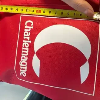 Contrôle au mètre ruban des dimensions du logo sérigraphié sur un panier magasin rouge Charlemagne